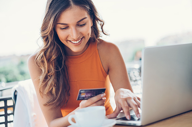 woman on her computer while looking at her credit card